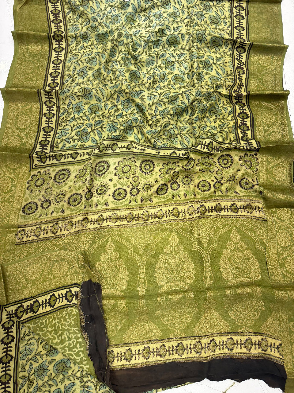 An olive green Banarasi silk saree with intricate gold, blue, and black floral patterns and borders, displayed flat.