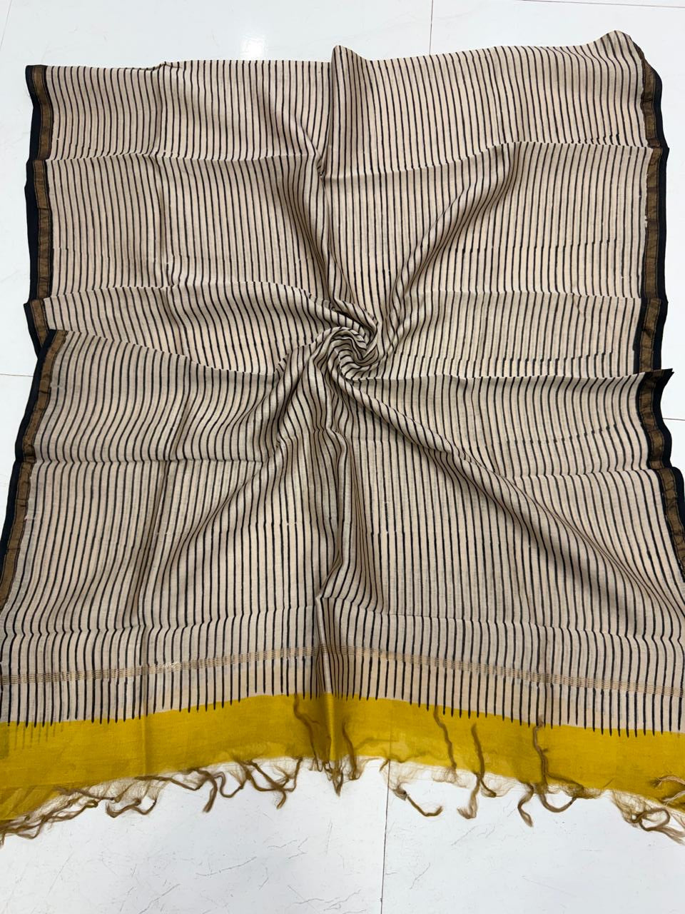 Folded Chanderi silk dupatta featuring vertical black stripes on a cream base, detailed with a bold mustard yellow border and traditional handblock printed motifs.