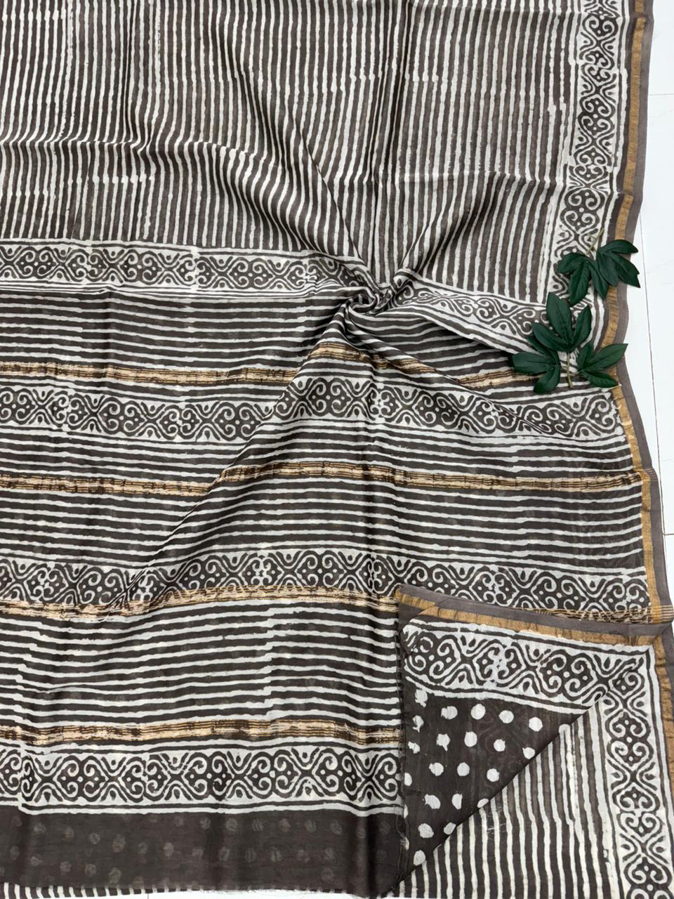 A handcrafted Chanderi silk saree featuring traditional Dabu mud-resist handblock printing and a shimmering gold zari border.