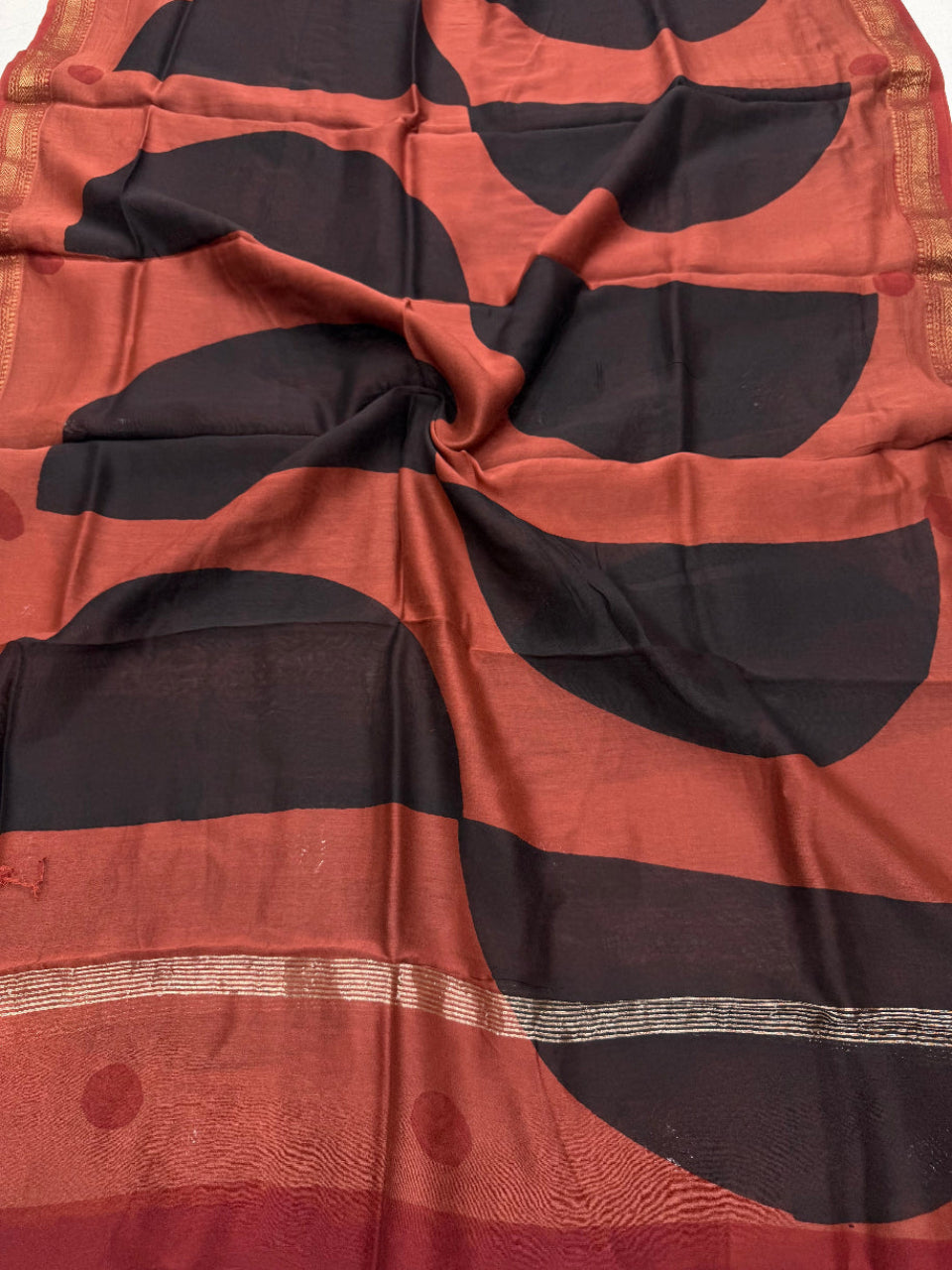 Detailed view of the pure Maheshwari silk dupatta with bold, alternating diagonal blocks of black and rust, finished with an elegant handloom woven golden Zari border.