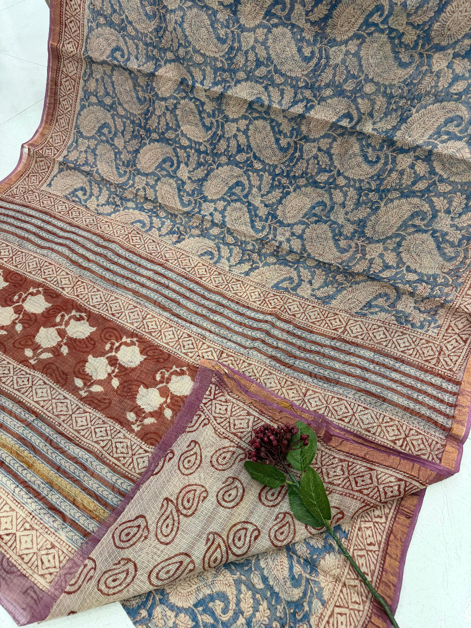 Patterned fabric with paisley design in blue, brown, and beige on a white background