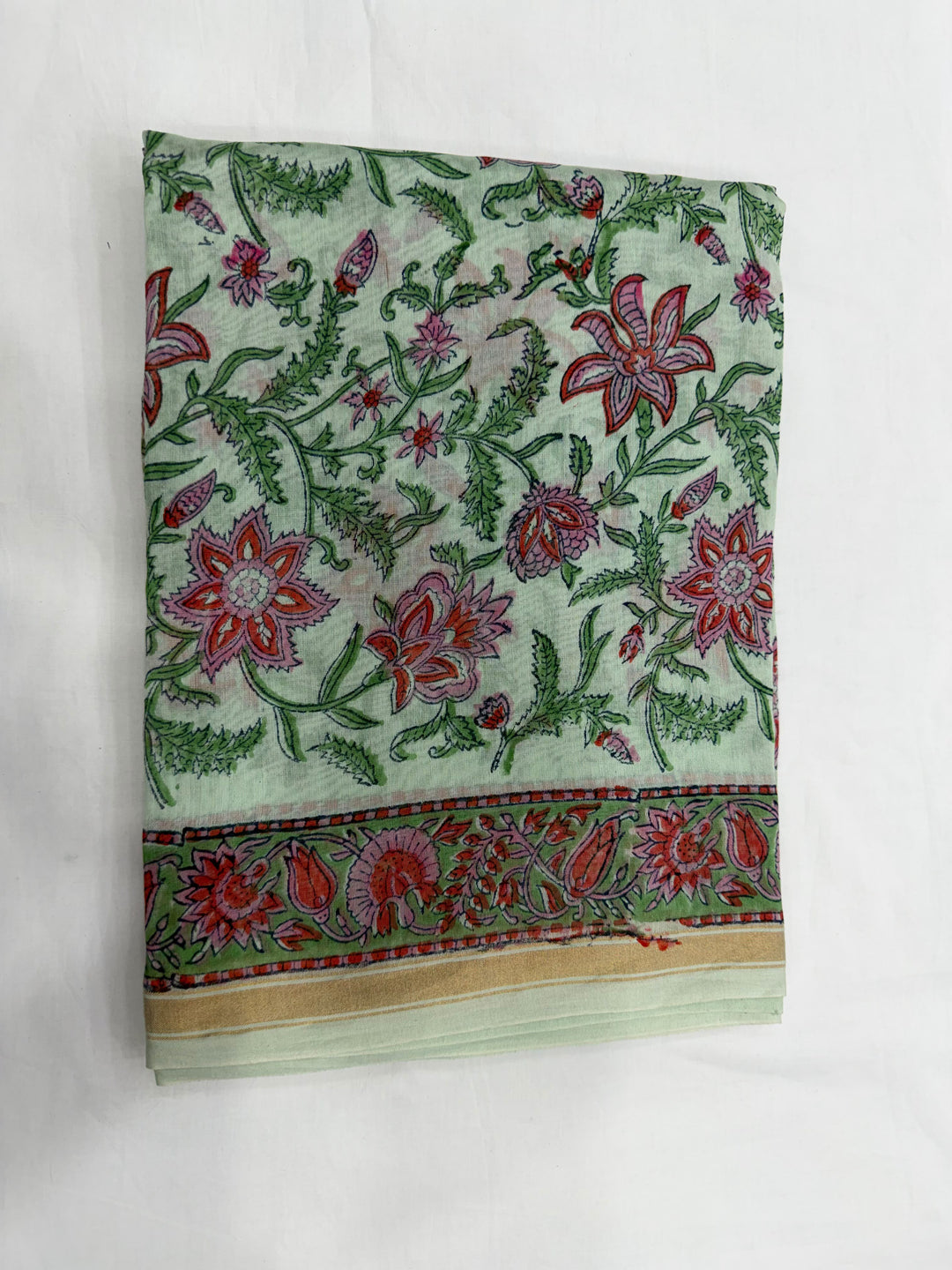 A folded piece of light green Chanderi silk kurta fabric featuring a detailed floral block print in red, pink, and green, highlighted by a decorative patterned border along the edge.