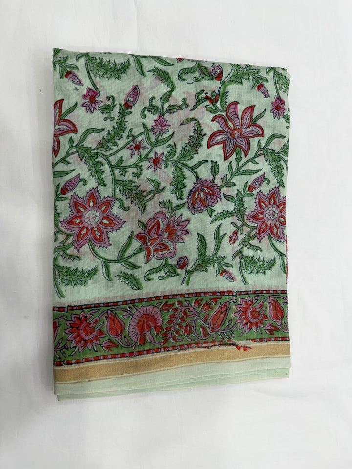A folded piece of light green Chanderi silk kurta fabric featuring a detailed floral block print in red, pink, and green, highlighted by a decorative patterned border along the edge.
