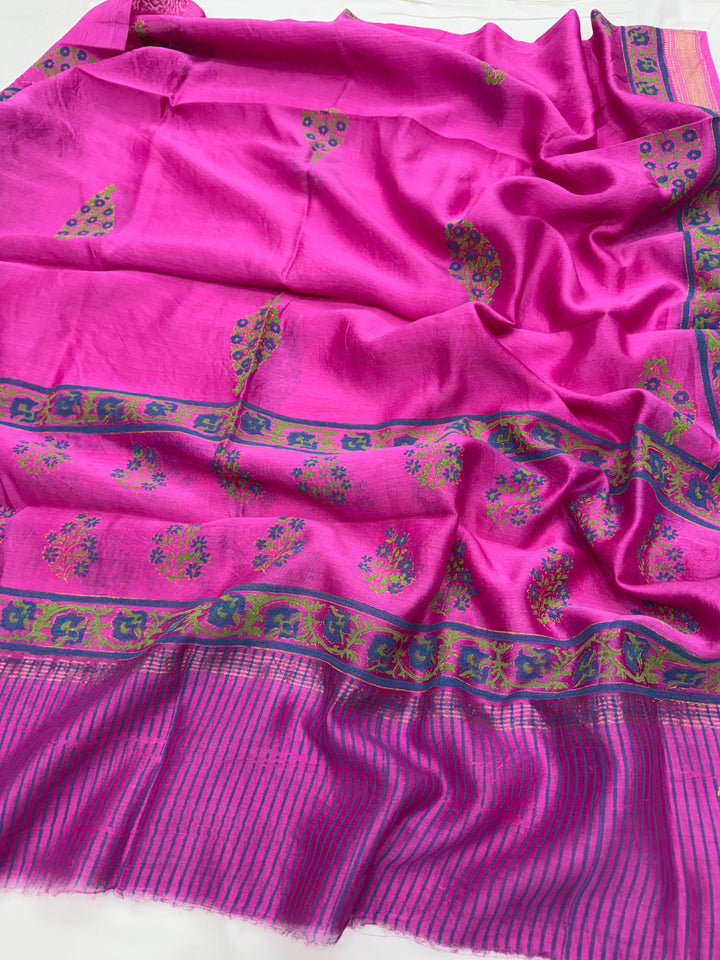 A vibrant magenta pink Maheshwari silk dupatta featuring intricate blue, green, and gold woven floral motifs along with a traditional striped border.