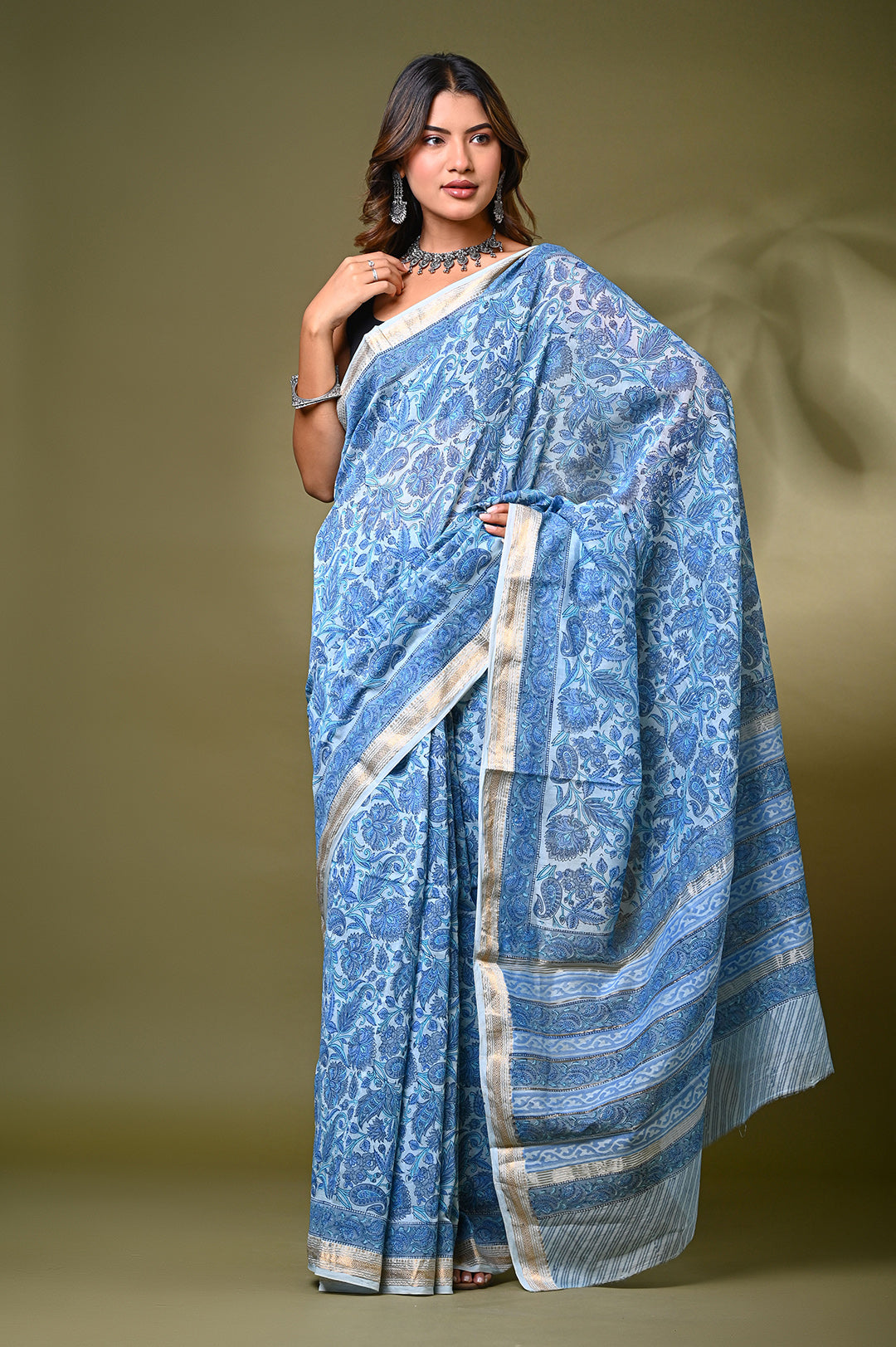 Model wearing a light blue Sanganeri hand-block floral print Maheshwari silk-cotton saree with a classic gold zari border and matching unstitched blouse piece.