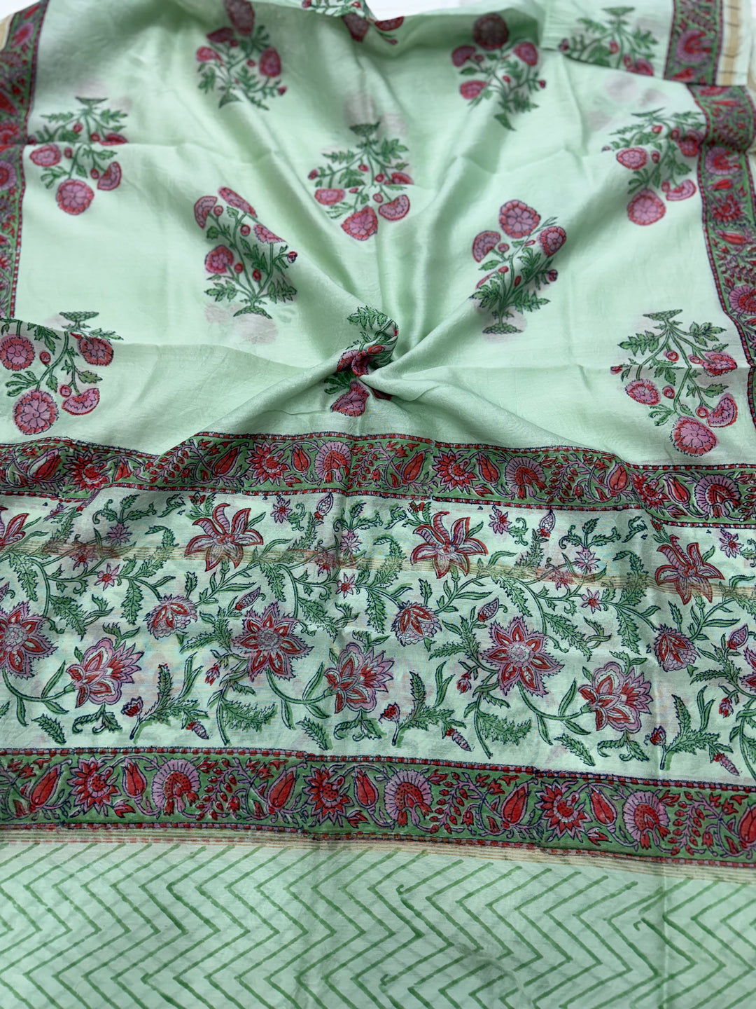 A mint green Chanderi silk dupatta featuring delicate pink and green floral block print motifs, highlighted by a wide patterned border with traditional ethnic designs.