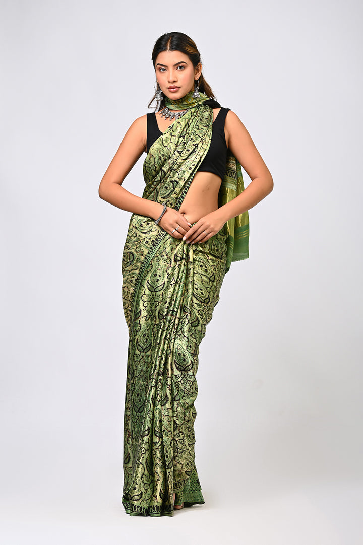 A woman modeling a natural green Ajrakh Vanaspati print Modal Silk saree with a geometric Lagdi Patta design by Bagru Hastkala Printers.