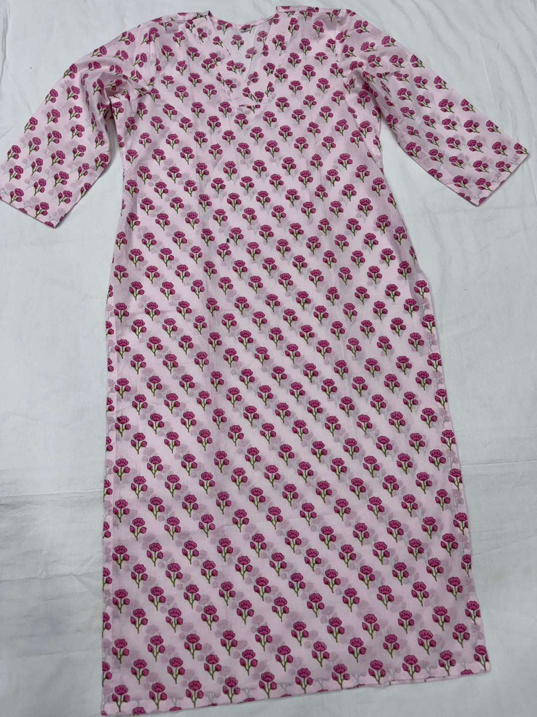 Close-up shot of a baby pink cotton kurta showing the elegant V-neckline and intricate pink floral block print details.