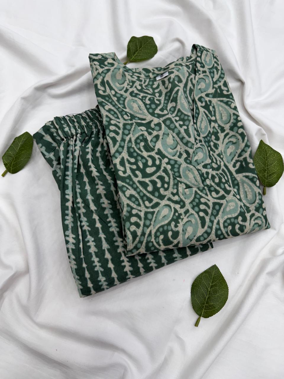 Ek hansti hui model ne green color ka Bagru hand block print kurta aur matching pant co-ord set pehna hua hai, background me traditional Rajasthani architecture aur ek pool dikh raha hai.