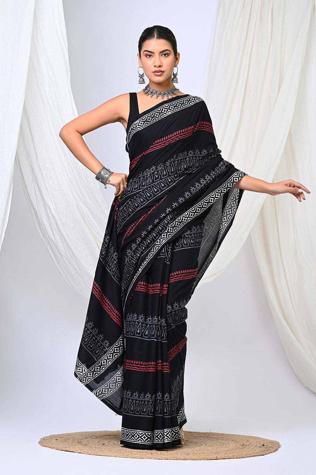 A woman modeling a traditional Bagru hand block print soft mulmul cotton saree in classic black, white, and red motifs.