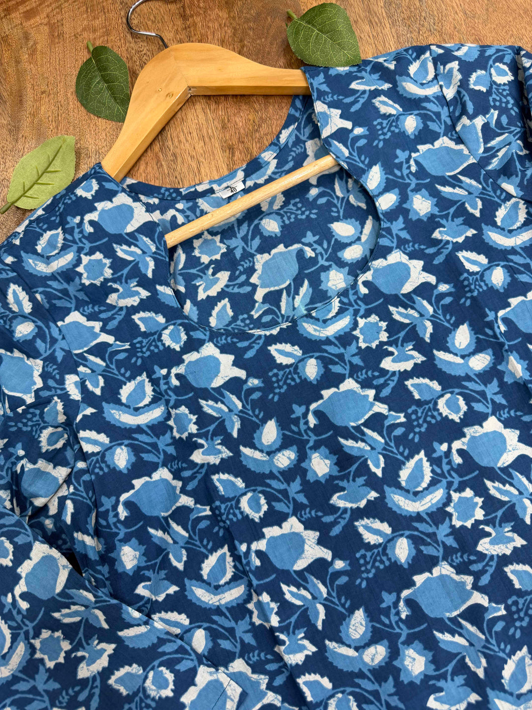 Natural indigo blue dye se bana Bagru hand block print floral cotton kurta, jo white background par fold karke display kiya gaya hai.