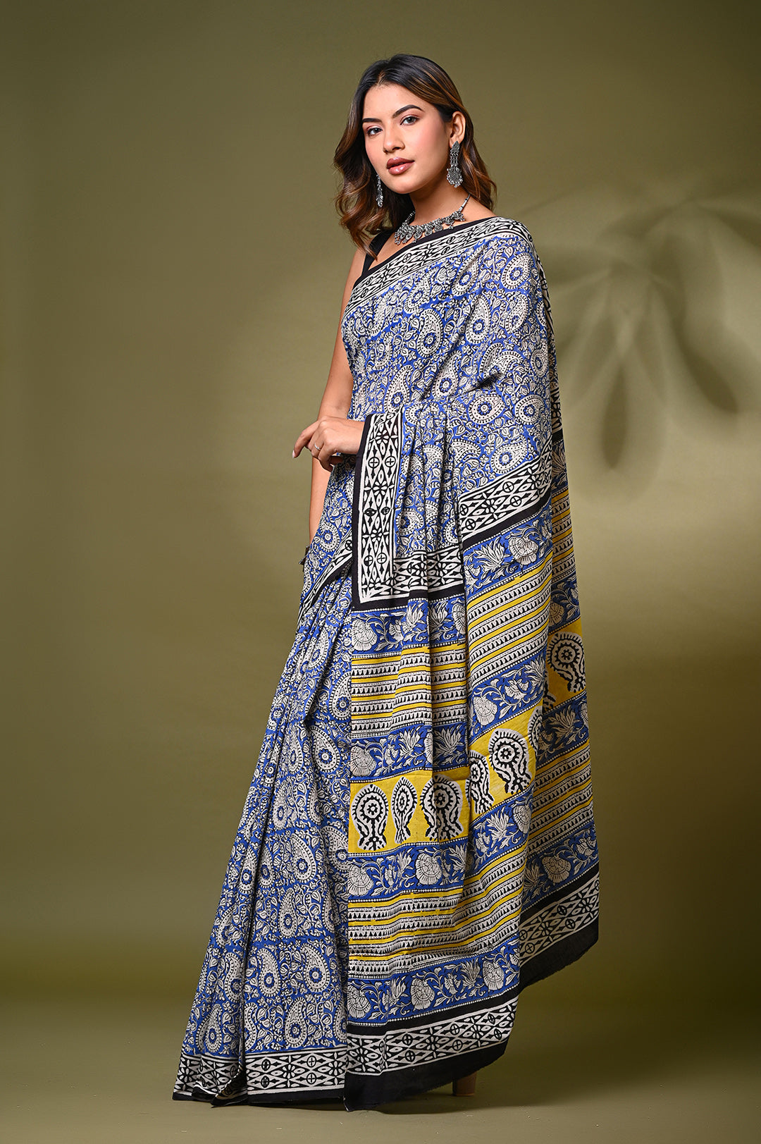 Front view of a model in an authentic Bagru handblock print mulmul cotton saree, showcasing intricate paisley (kairi) motifs in traditional blue and off-white natural dyes with a vibrant yellow patterned border.