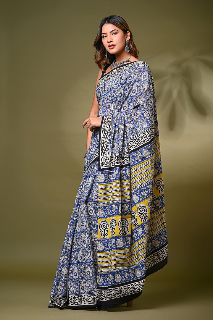 Front view of a model in an authentic Bagru handblock print mulmul cotton saree, showcasing intricate paisley (kairi) motifs in traditional blue and off-white natural dyes with a vibrant yellow patterned border.