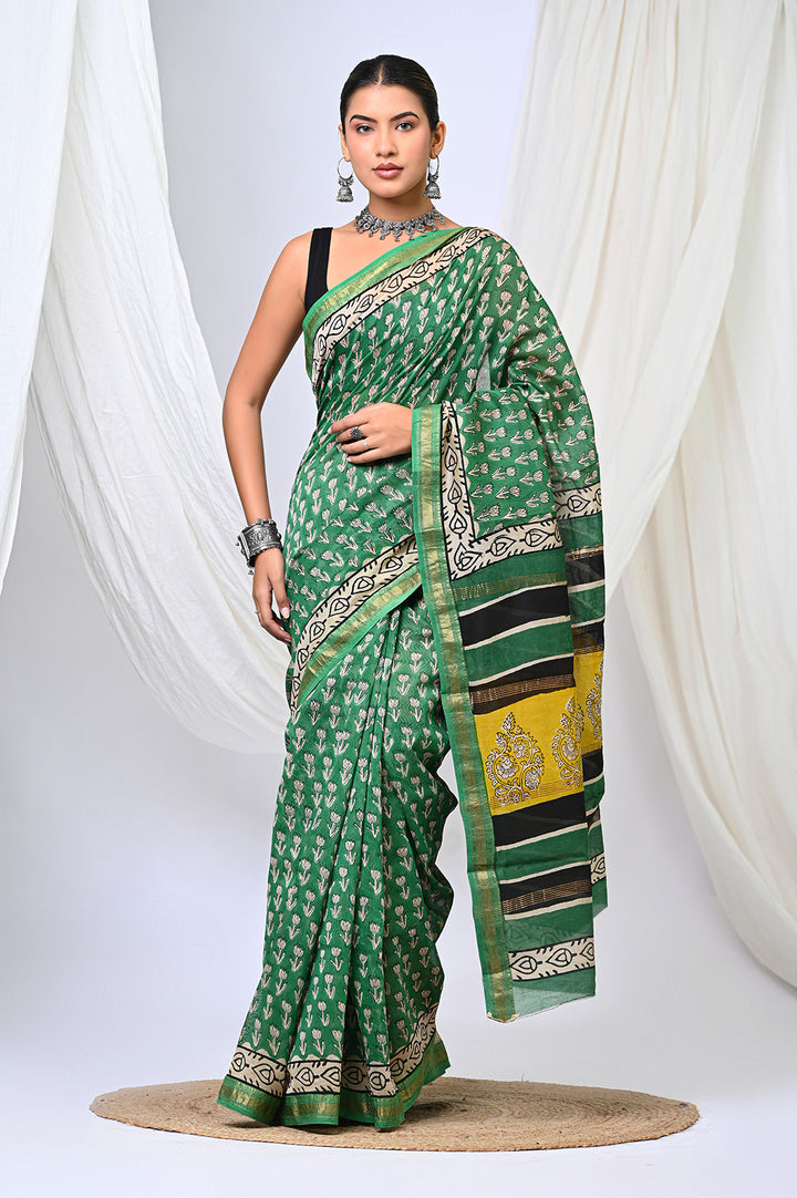 A woman modeling a natural green Bagru handblock print Maheshwari Silk saree with delicate white buti motifs and a traditional black, white, and yellow patterned border.
