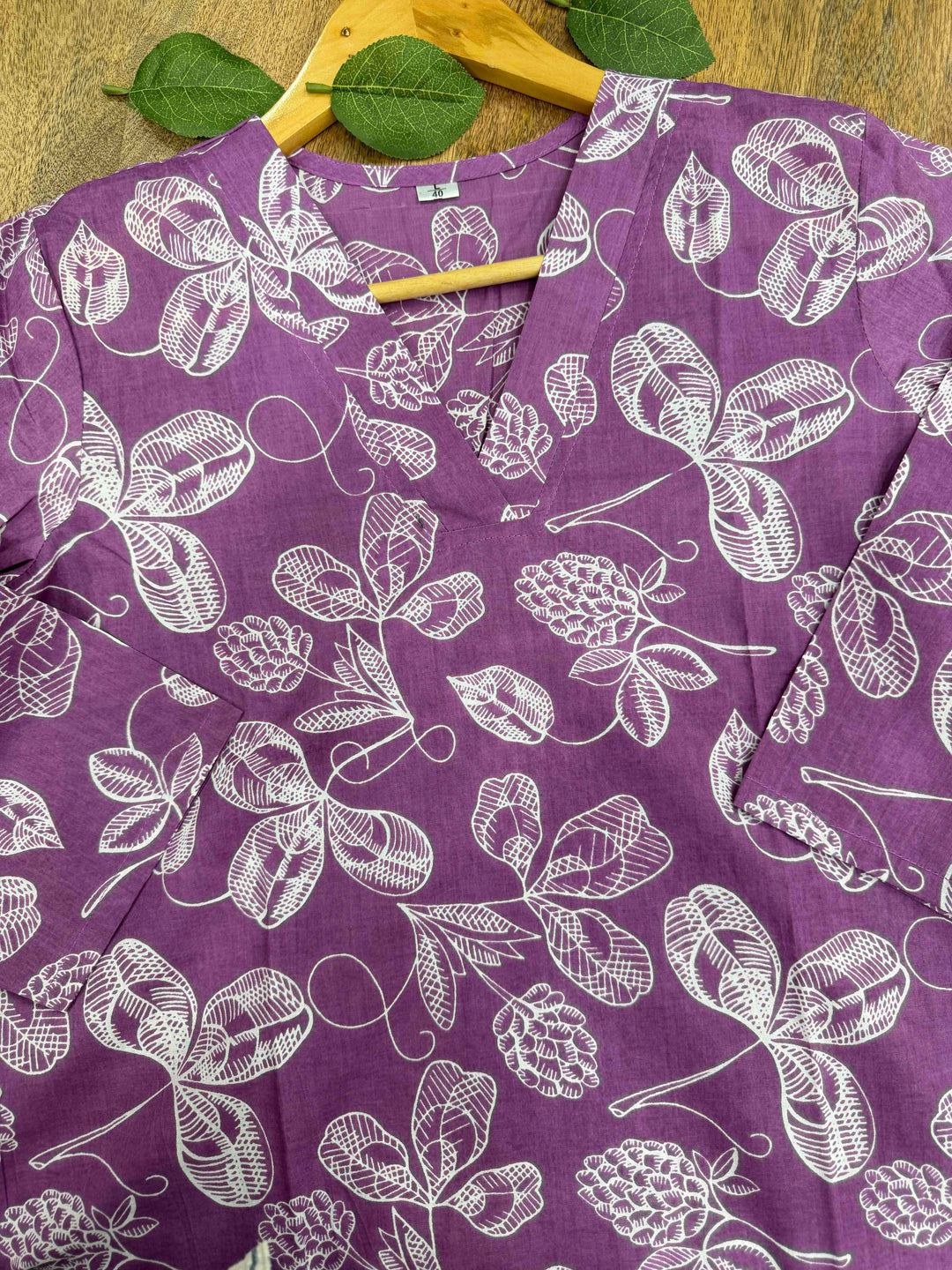 Purple background par safed rang ke pine-cone aur floral motifs waala Bagru hand block print cotton kurta, white cloth background par displayed