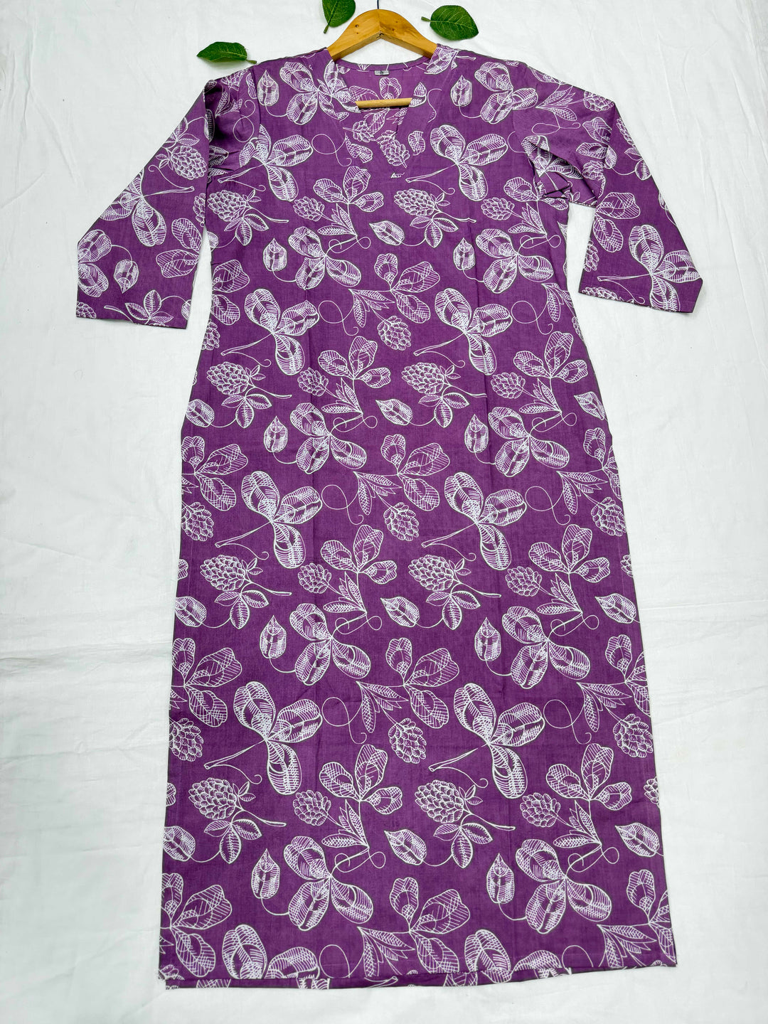 Purple background par safed rang ke pine-cone aur floral motifs waala Bagru hand block print cotton kurta, white cloth background par displayed.