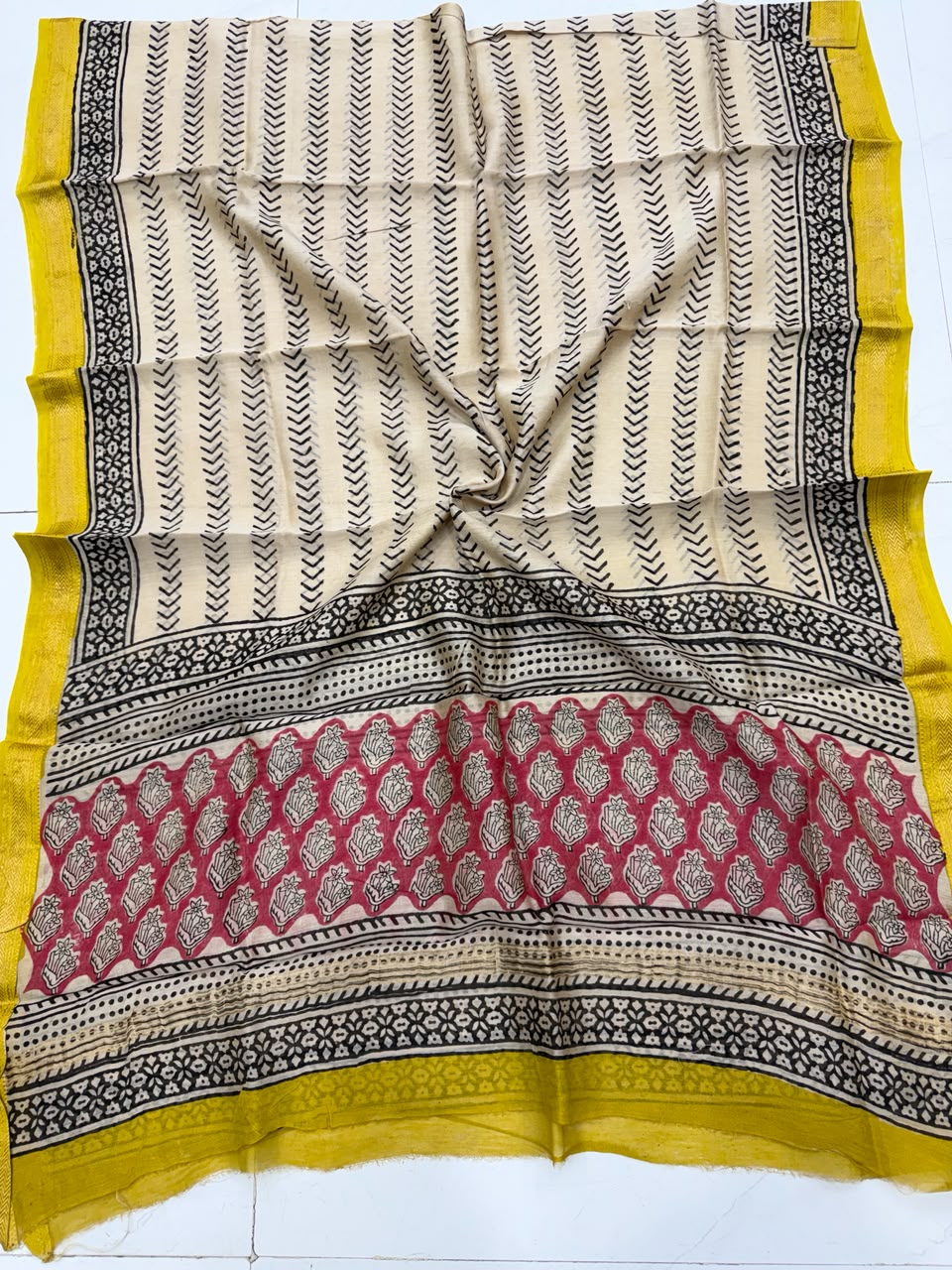 Detailed view of the cream handloom Maheshwari silk dupatta, highlighting the intricate black chevron patterns, red floral block-printed borders, and a vibrant yellow handloom woven border.