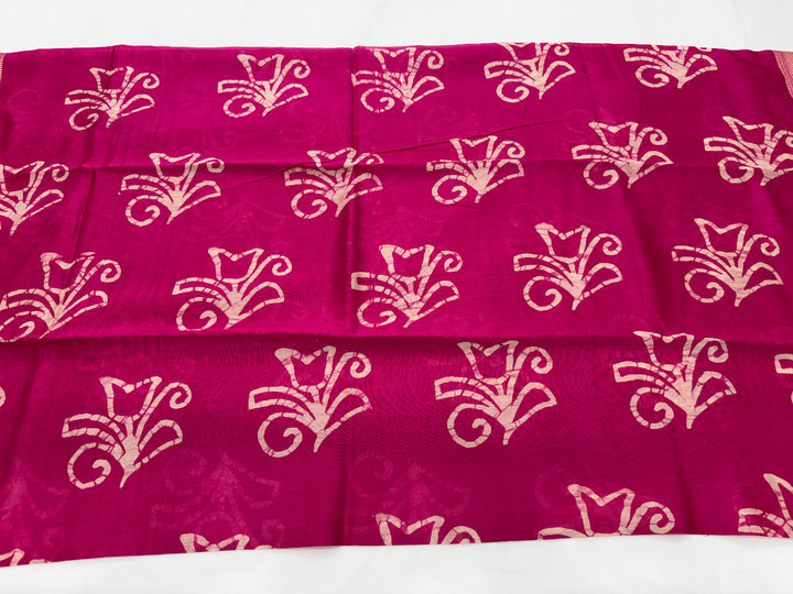 A close-up of a magenta pink fabric with a repeating beige floral or paisley-style woven pattern, laid flat against a white background.
