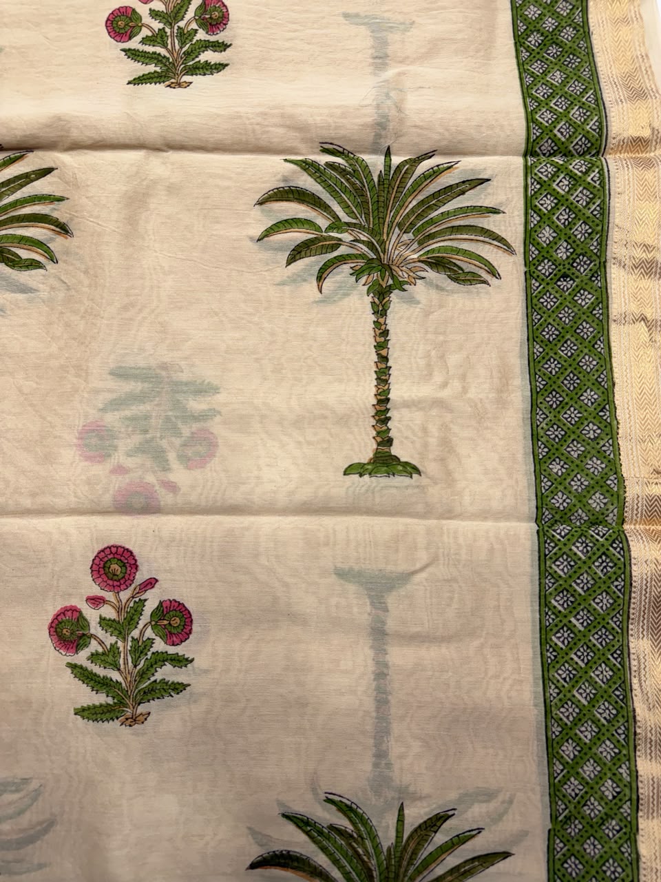 Close-up of the unstitched beige Maheshwari silk kurta fabric, showcasing beautiful pink and green hand block printed floral bootis and a geometric woven border.
