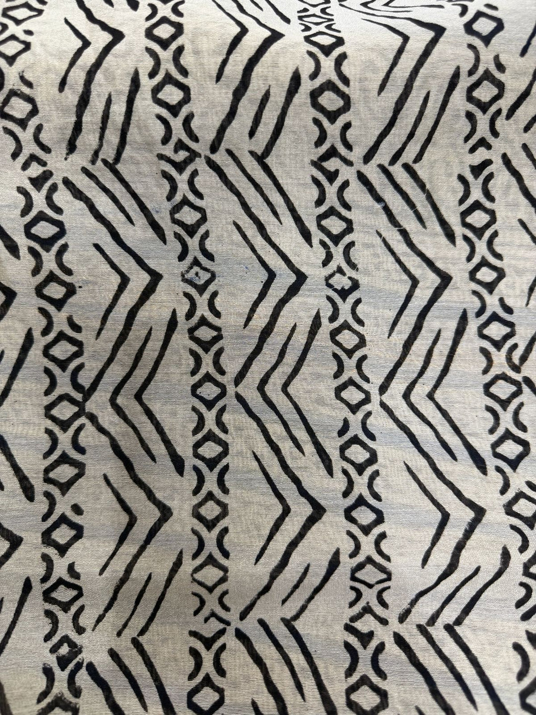Close-up detail of a Chanderi Silk saree featuring traditional black hand-block printed geometric patterns, zigzag lines, and circular motifs on a natural off-white background.