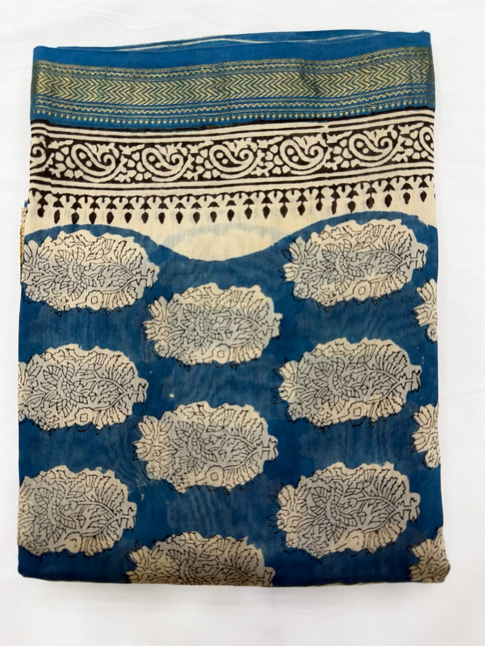 Close-up of the unstitched deep blue Maheshwari silk kurta fabric, showcasing the traditional all-over beige floral coin and leaf motifs hand-stamped by the master artisans of Bagru.