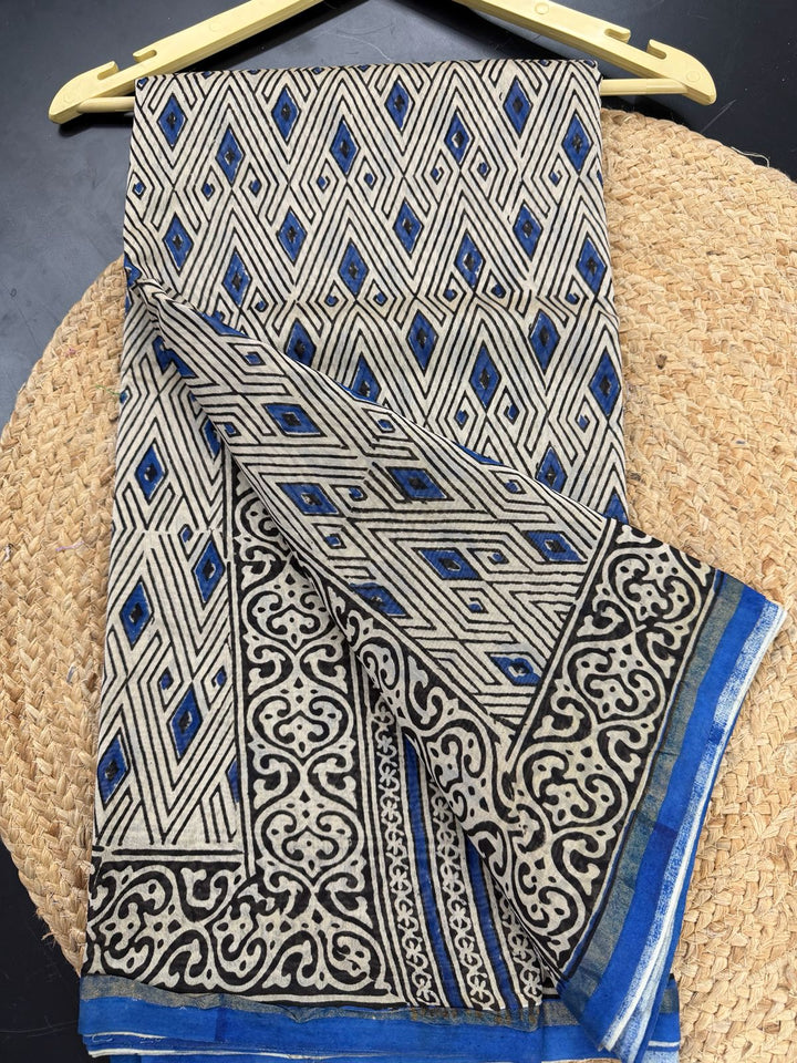 Close-up of a white and blue Chanderi Silk saree featuring intricate geometric diamond block prints on the body and a traditional gold-accented floral border.