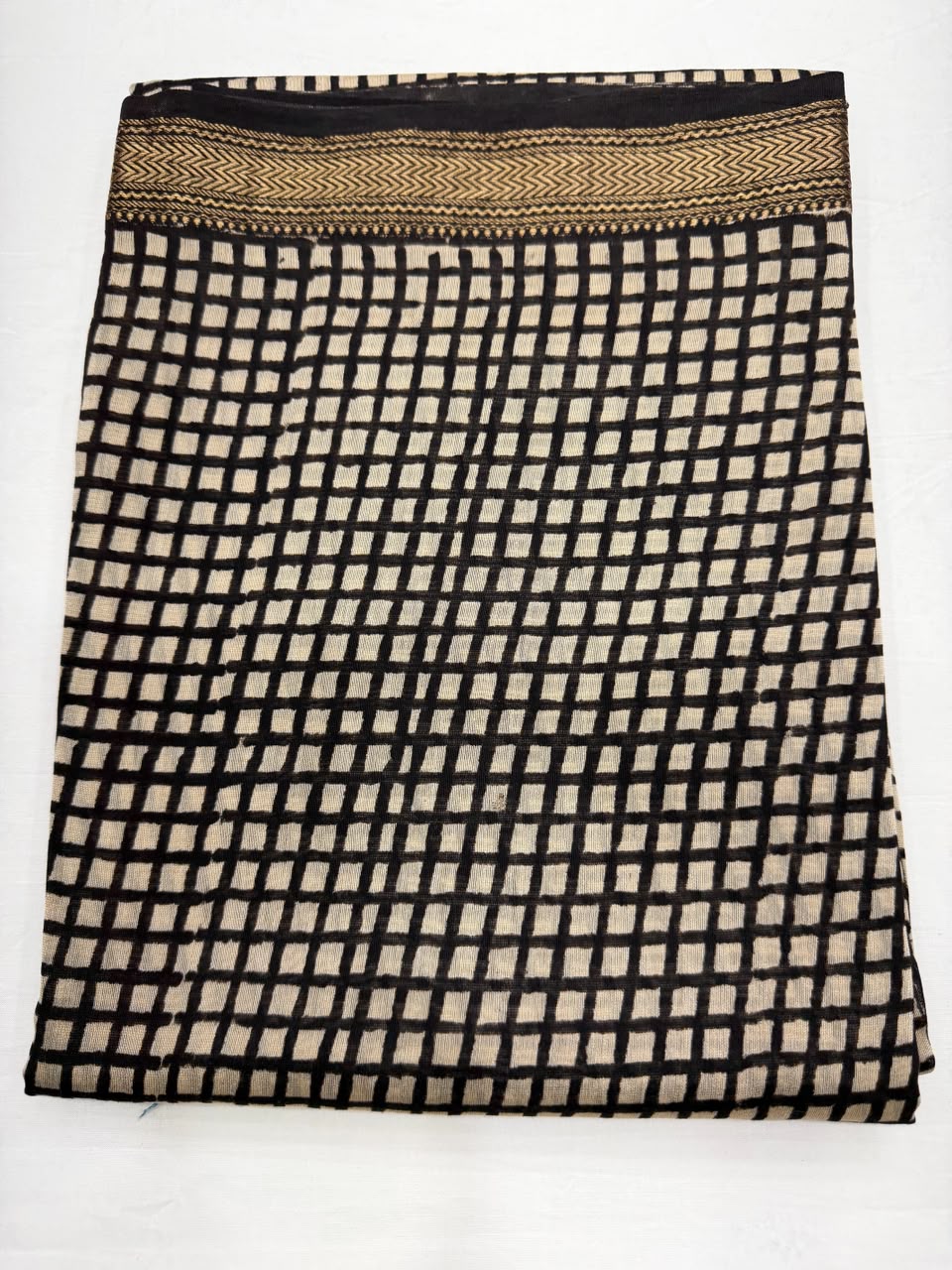 Close-up of the unstitched cream Maheshwari silk kurta fabric, highlighting the traditional crisp geometric black check patterns hand block printed by master artisans of Bagru, Rajasthan.