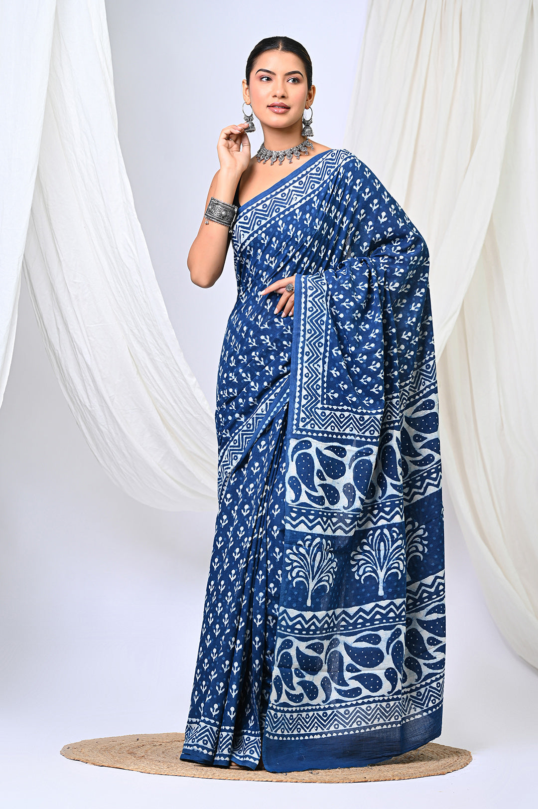 Full-length front view of a model in an authentic pure indigo blue Dabu handblock print mulmul cotton saree, showcasing delicate white buti motifs and a detailed tree-patterned pallu.