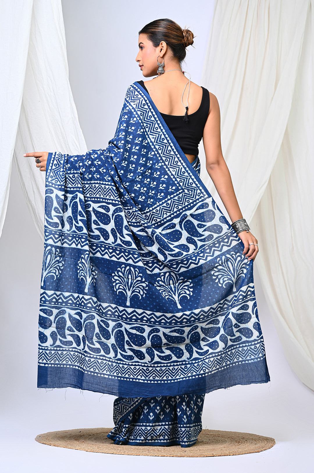 Rear view of a model showcasing the detailed pallu of a pure indigo blue Dabu handblock print mulmul cotton saree, featuring traditional white tree motifs and geometric block-printed borders.
