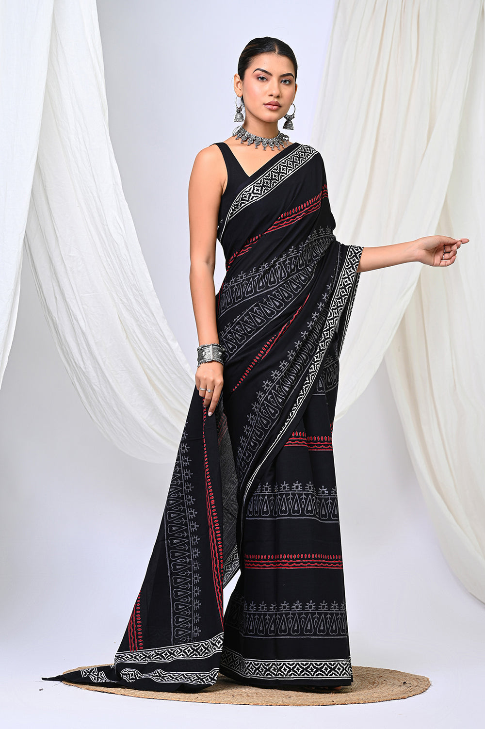 Full-length view of a feather-light soft mulmul cotton saree featuring an all-over designer black and white block printed pattern with a red border.