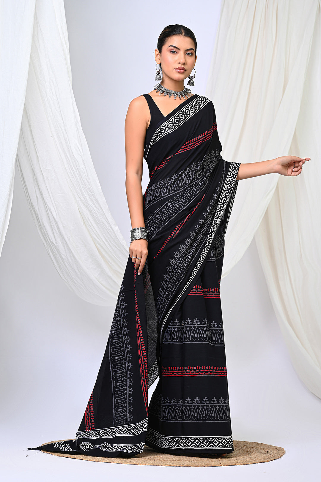 Full-length view of a feather-light soft mulmul cotton saree featuring an all-over designer black and white block printed pattern with a red border.