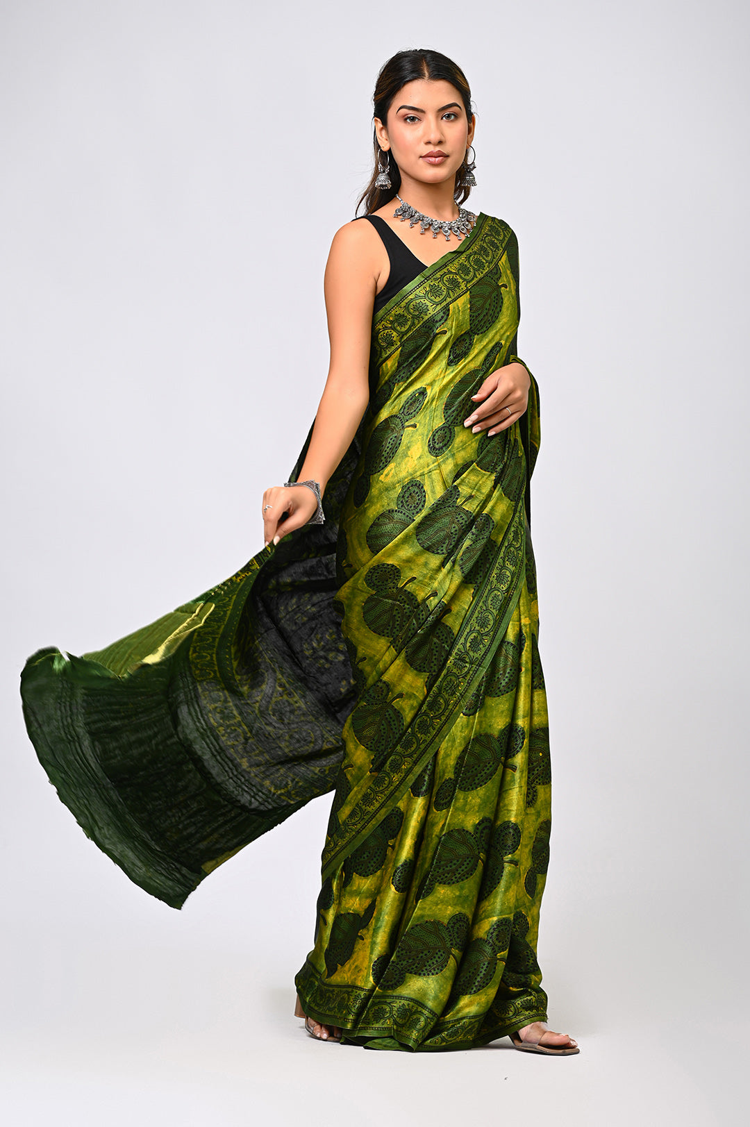 A woman modeling a natural green Pomegranate Dye Modal Silk saree with a flowing, printed pallu by Bagru Hastkala Printers.