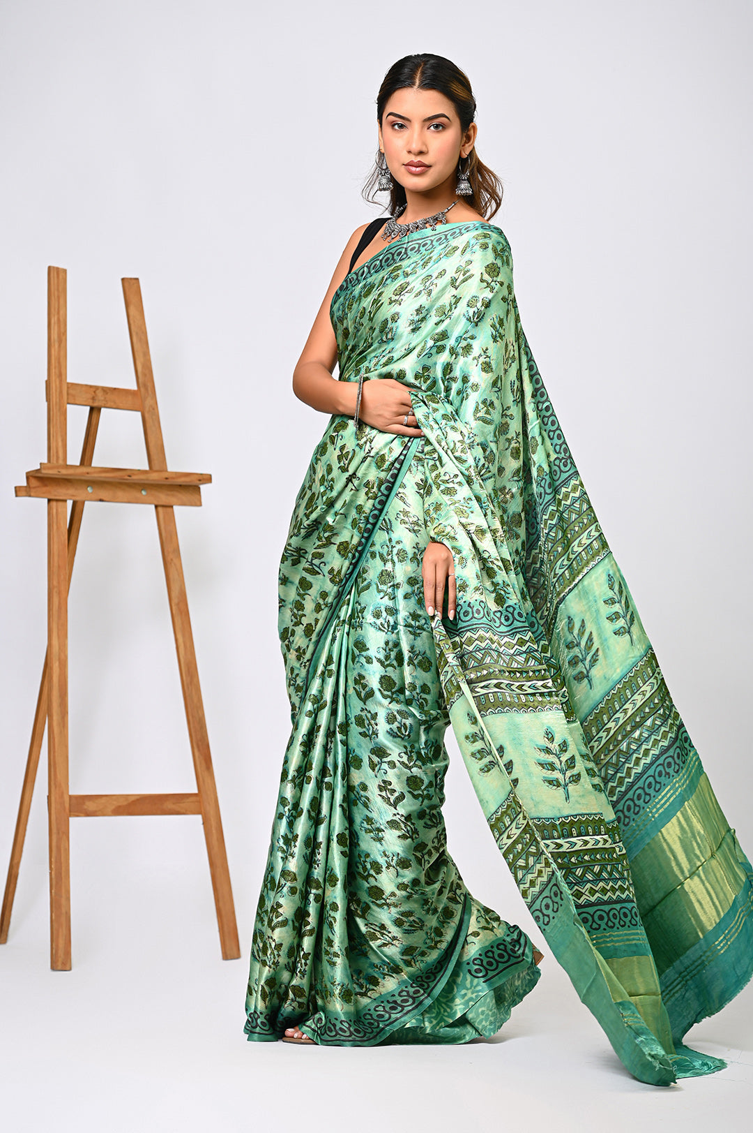 An authentic herbal-dyed green Modal Silk saree with a repeating geometric block print design and a classic running border, styled against a plain white background.
