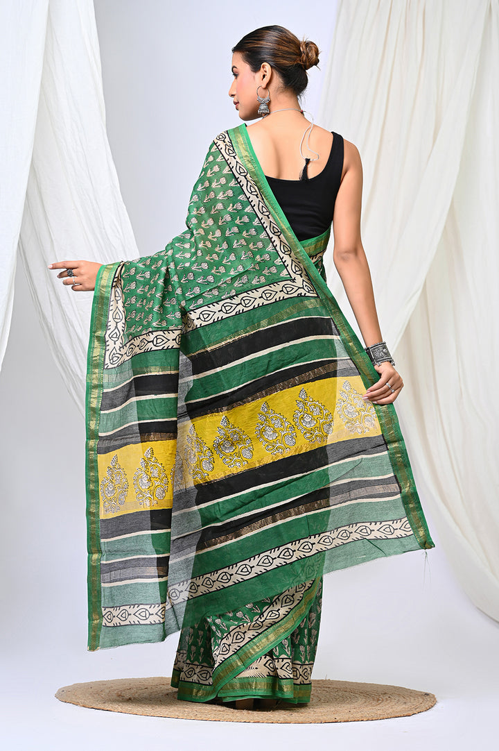 A premium green Maheshwari silk saree with white buti print patterns and a contrasting black and yellow pallu border, modeled against a soft white background.