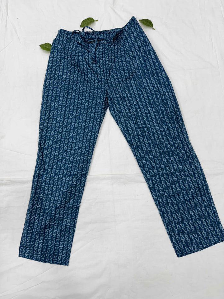 Close-up view of indigo blue straight-leg pants featuring an all-over small geometric print pattern, laid flat on a white fabric background.