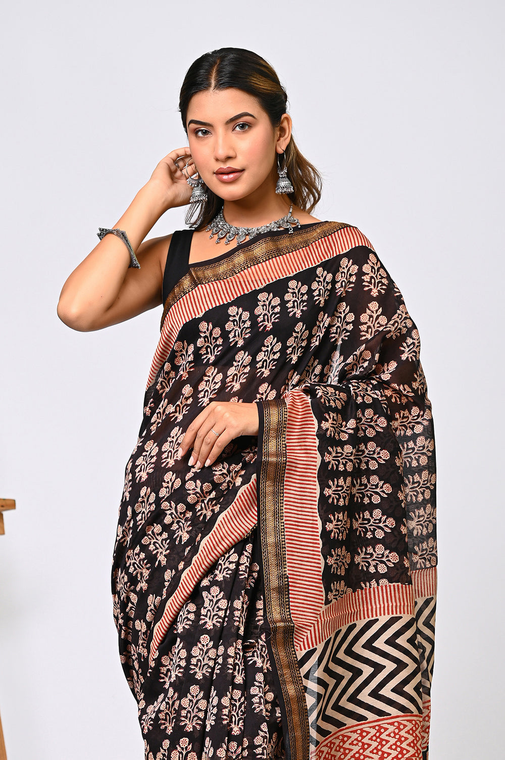 Full-length view of a black Maheshwari silk saree handcrafted by Bagru Hastkala Printers using natural iron mud dye, detailed with traditional rust floral prints and a patterned pallu.