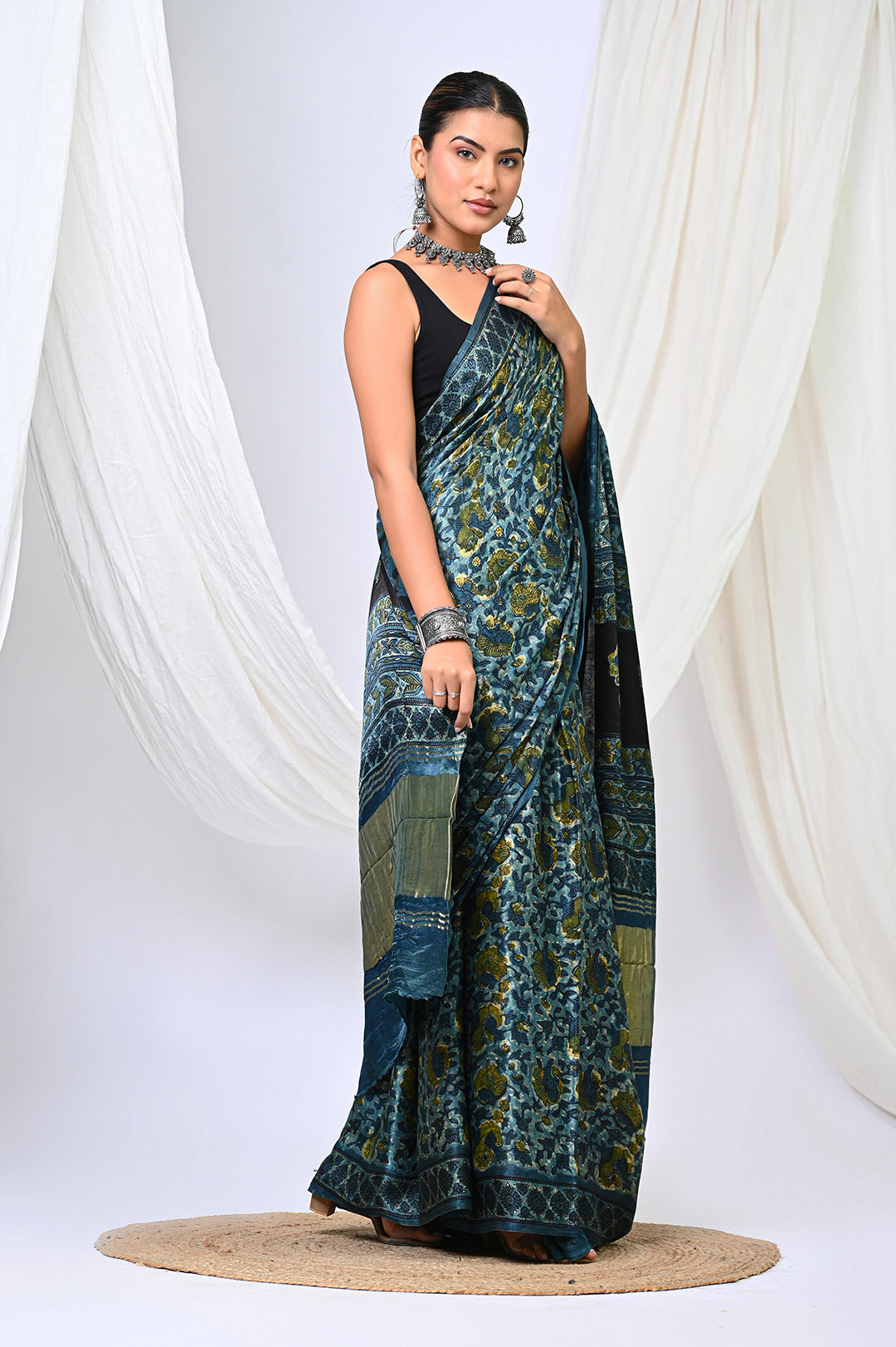 A woman modeling an Ajrakh Modal Silk saree in deep natural indigo blue and vanaspati green hand block print by Bagru Hastkala Printers.