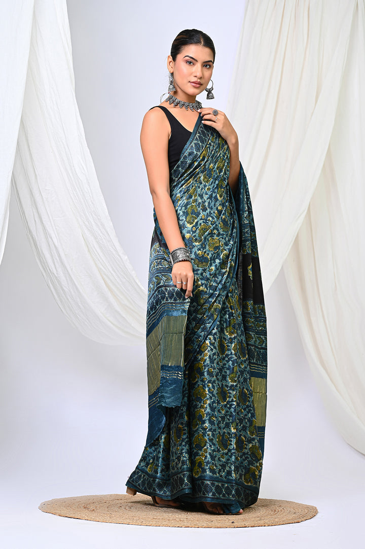 A woman modeling an Ajrakh Modal Silk saree in deep natural indigo blue and vanaspati green hand block print by Bagru Hastkala Printers.