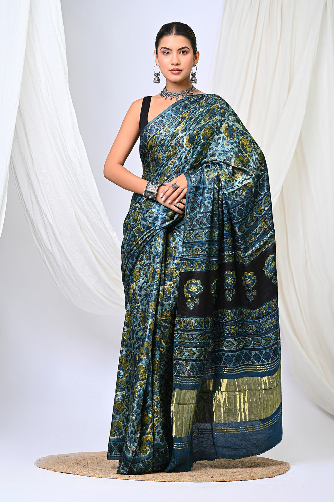 A woman modeling an Ajrakh Lagdi Patta Modal Silk saree in deep natural indigo blue and vanaspati green print by Bagru Hastkala Printers.