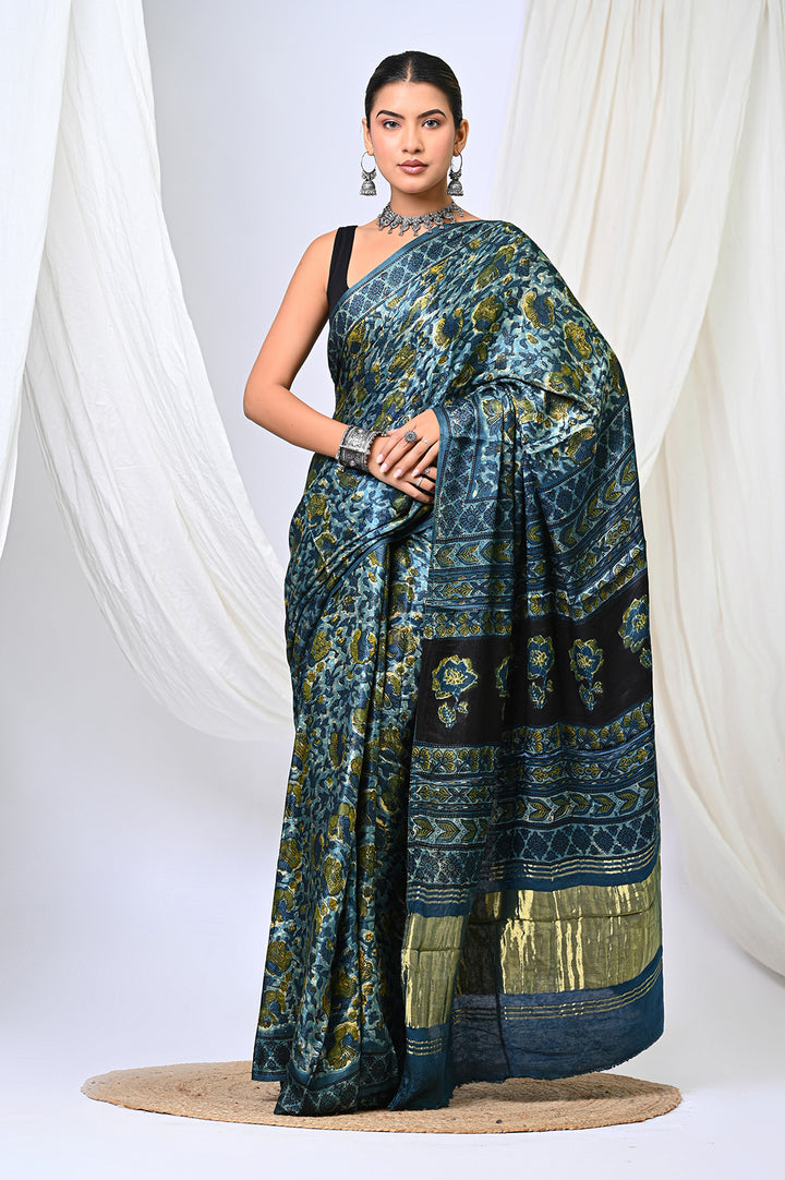 A woman modeling an Ajrakh Lagdi Patta Modal Silk saree in deep natural indigo blue and vanaspati green print by Bagru Hastkala Printers.