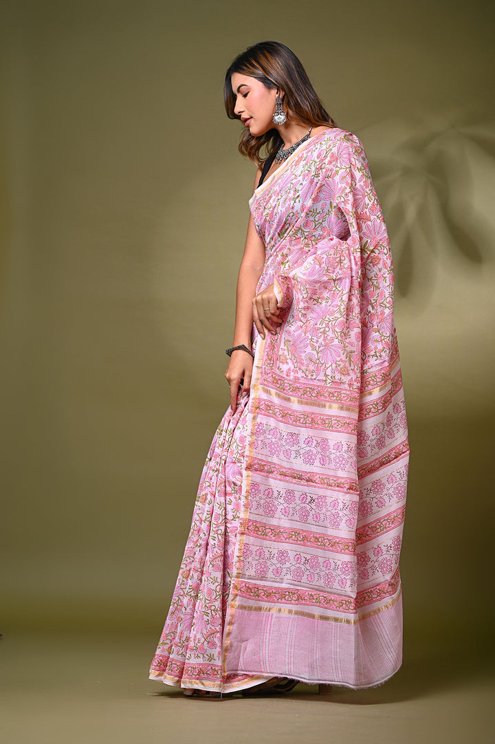 An authentic handblock printed baby pink Chanderi silk saree with a detailed continuous floral net design and running geometric borders, styled with a black sleeveless blouse.