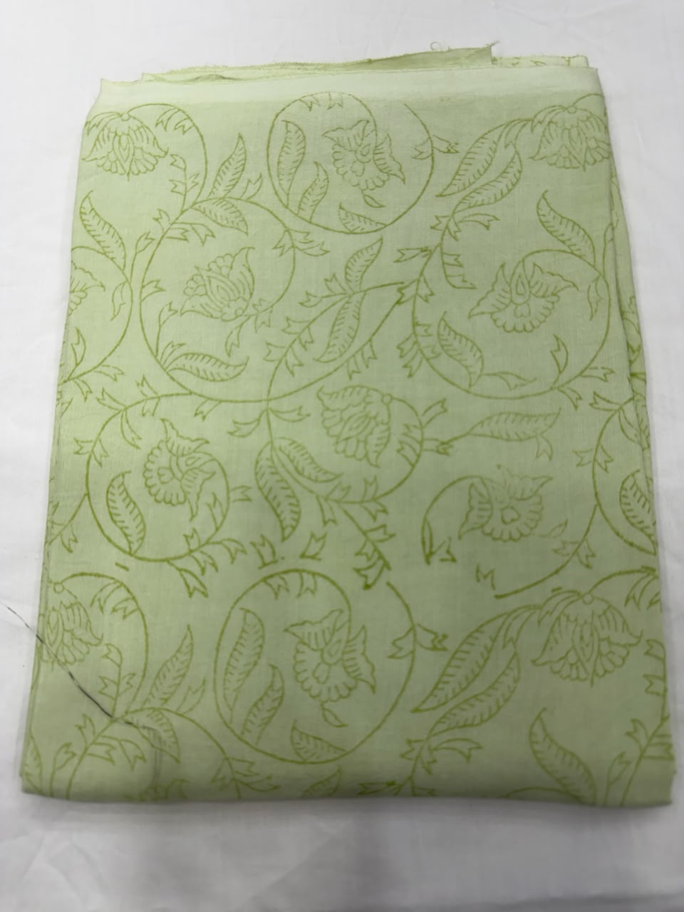 Premium quality unstitched Santoon silk bottom fabric in a refreshing pista green color with subtle line patterns, neatly rolled for the contrast Maheshwari silk suit set.
