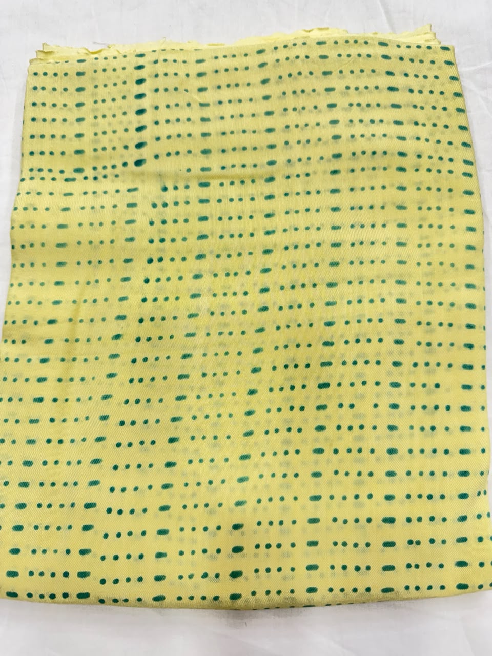 Premium quality unstitched Santoon silk bottom fabric in a contrasting green color with an elegant block print pattern, neatly folded for the bright yellow Maheshwari silk suit set.