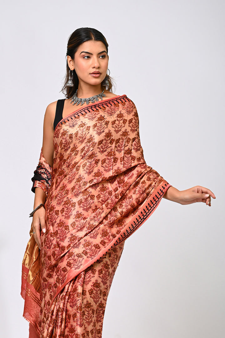 An authentic plant-based Vanaspati dyed Modal Silk saree in natural brick red and black, showing the fluid drape and intricate hand block prints against a plain white background.