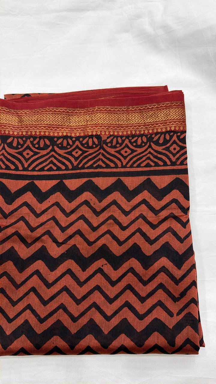 Close-up of the unstitched Maheshwari silk kurta fabric, featuring a sharp, traditional geometric zigzag (leheriya-inspired) block print in black and earthy rust tones.