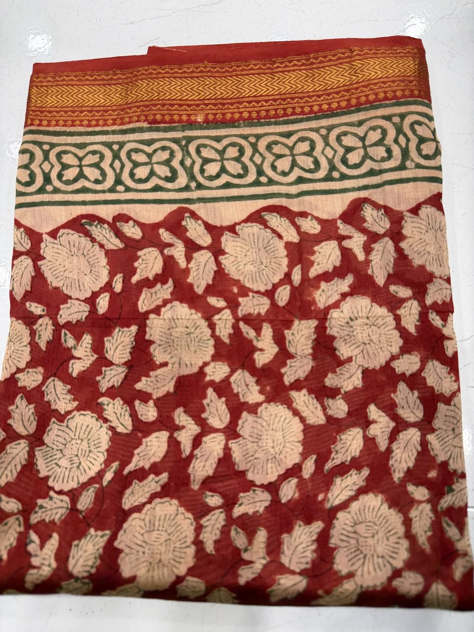 Close-up of the unstitched Maheshwari silk kurta fabric, featuring intricate, traditional all-over floral block print patterns in rich rust red and cream tones.