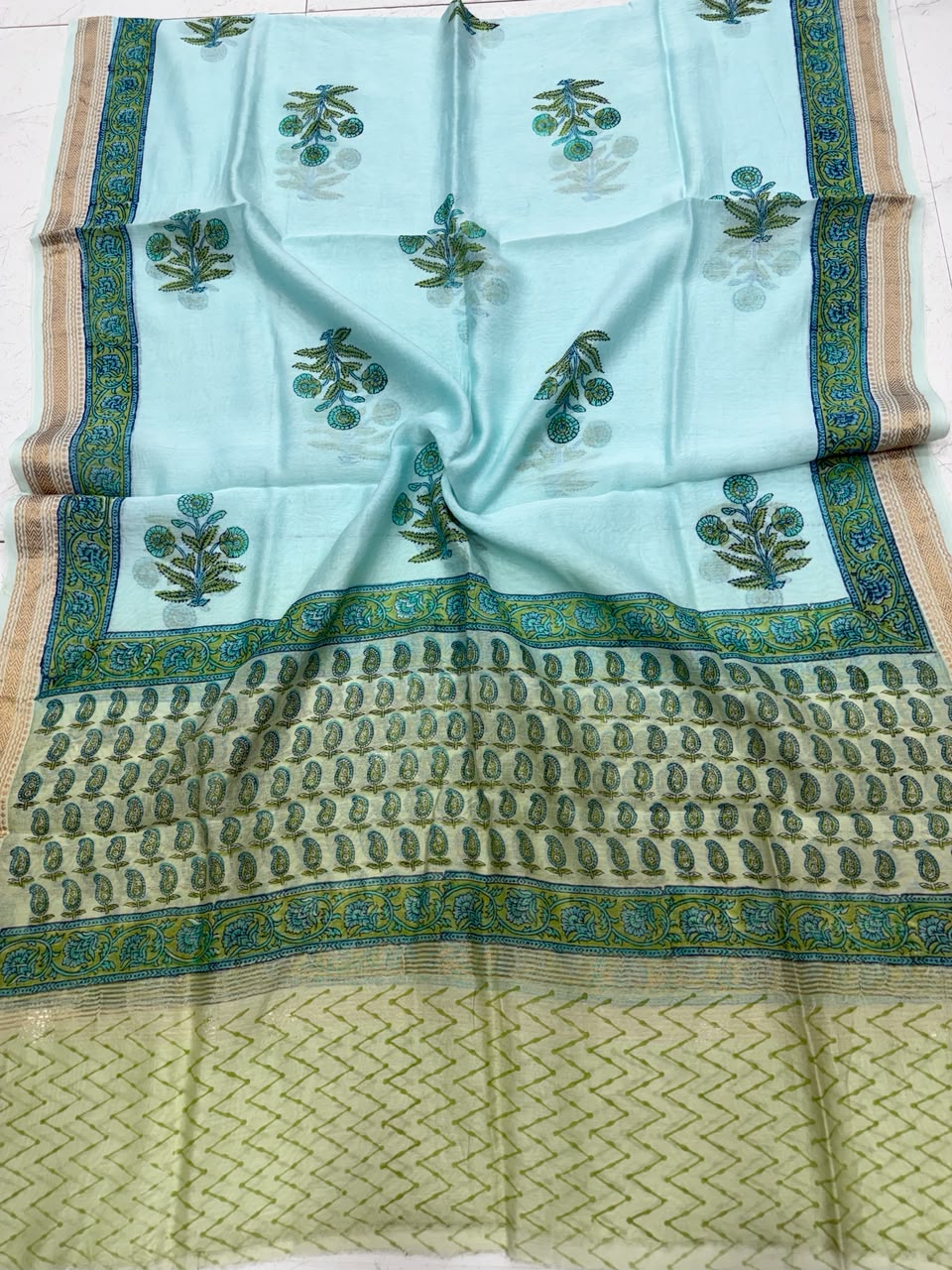 Detailed view of the turquoise handloom Maheshwari silk dupatta, highlighting the intricate Sanganeri traditional floral patterns, a light green border section, and a rich handloom woven golden Zari border.