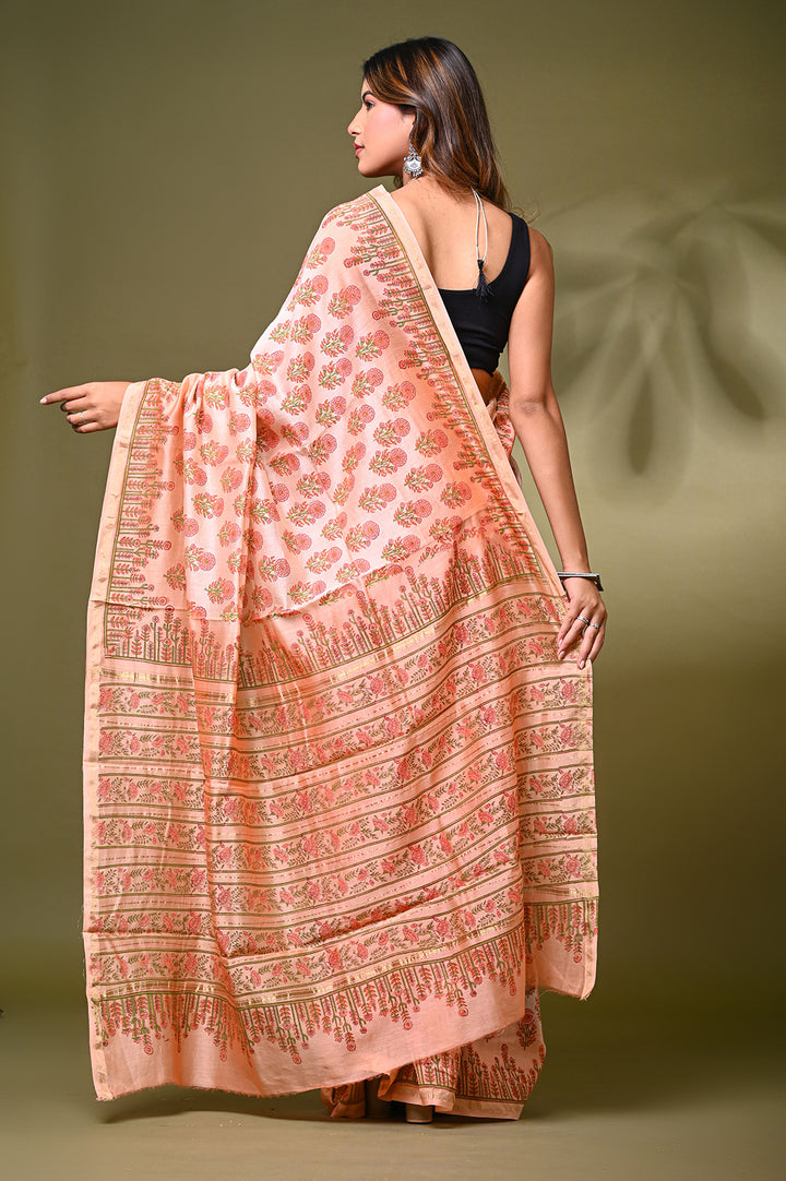 Full-length view of a traditional peach Chanderi silk saree featuring hand-stamped Sanganeri floral buti motifs and an elegant matching pallu, styled with a black sleeveless blouse.