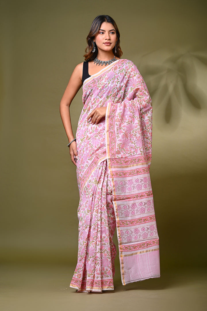 A woman modeling a baby pink Sanganeri print Chanderi Silk saree featuring an all-over intricate floral jaal lattice pattern, structured borders, and a matching patterned pallu against a soft olive green backdrop.