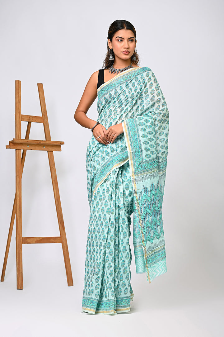 A woman modeling a light green Sanganeri print Chanderi Silk saree featuring delicate hand block printed floral buti motifs, a structured geometric border, and a shimmering sheer drape.